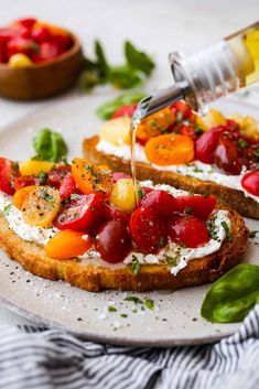 someone is pouring olives onto some bread with tomatoes and other vegetables on it,