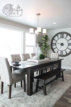 a dining room table with chairs and a clock on the wall