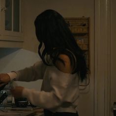 a woman standing in a kitchen preparing food on top of a stove next to an oven