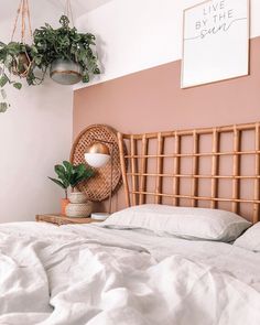 a bed with white linens and plants on the headboard, hanging above it