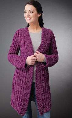 a woman wearing a purple cardigan standing in front of a gray background