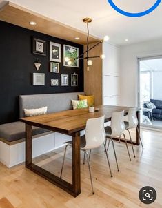 a dining room table with chairs and a bench in front of the wall that has pictures on it