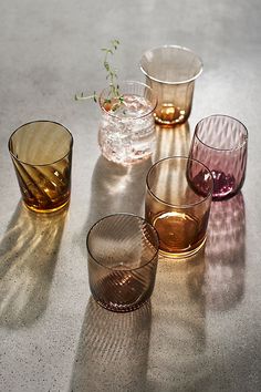 several different colored glasses sitting on top of a white table next to eachother