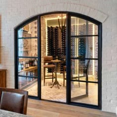 an arched glass door leads to a wine cellar in the middle of a dining room