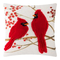 two red birds sitting on top of a white pillow