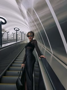 a woman is standing on an escalator with her hand in her pocket and luggage