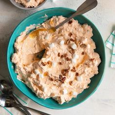 a bowl filled with mashed potatoes on top of a table next to spoons