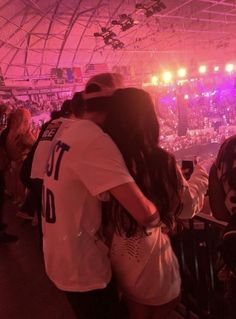 two people embracing each other in front of an audience at a concert with bright lights