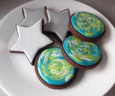 cookies decorated with icing and stars are on a white plate, ready to be eaten