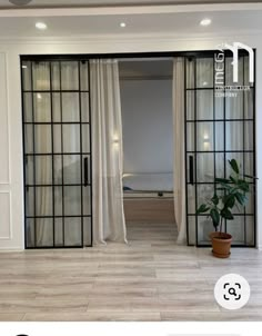 an open door leading to a bedroom with white walls and wood flooring, along with a potted plant