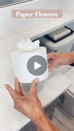 a person holding a toilet paper in front of a bathroom sink with the words paper flowers on it