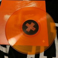 an orange vinyl record sitting on top of a black and white blanket