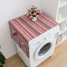 a washer sitting next to a book shelf with a flower arrangement on top of it