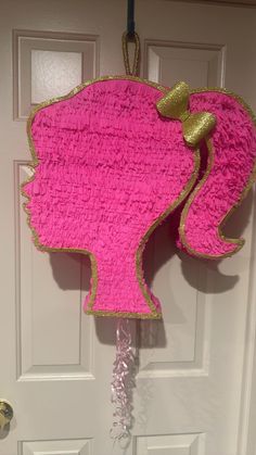 a pink and gold pinata shaped like a woman's head hanging from a door