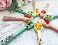 four toothbrushes decorated with different types of food on top of each other and flowers in the background