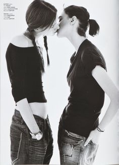 two women standing next to each other with their hands on their hipss and kissing