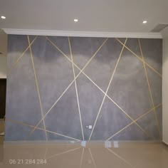 an empty room with grey walls and gold lines on the wall