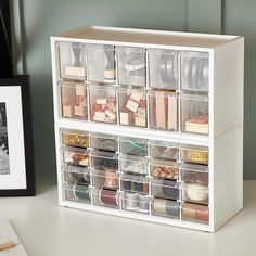 a white shelf with clear drawers filled with crafting supplies next to a black and white photo