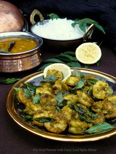 some food is sitting on a plate and next to other dishes that include rice, lemons, and curry