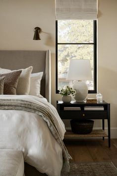 a bedroom with a bed, nightstand and window