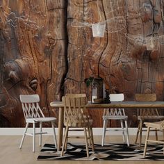 a dining room table and chairs in front of a wooden wall with peeling paint on it