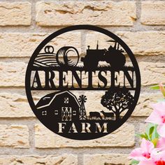 a metal sign on the side of a brick wall with flowers in front of it