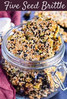 a jar filled with granola and nuts on top of a purple cloth next to a spoon