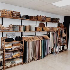 a room filled with lots of different types of clothes and baskets on shelving units