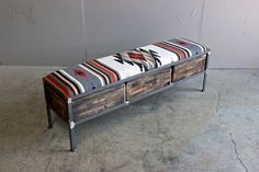 a bench made out of wood and metal with an upholstered blanket on top