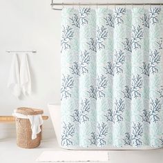 a white bath tub sitting next to a shower curtain with blue and green leaves on it