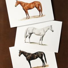 three different colored horses standing next to each other on top of a brown tablecloth