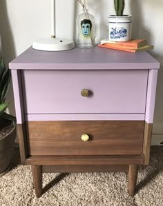 a purple and wood nightstand with two plants on top of it next to a potted plant