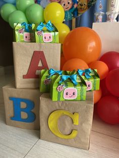 two gift bags with animals on them are sitting next to balloons and letters that spell out the word abc