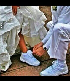 two people in wedding attire tying shoes on their feet while another person is sitting down