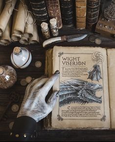 a person's hand on an open book surrounded by old books and other items