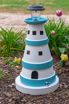 a white and blue lighthouse with a light on it's top sitting in the dirt