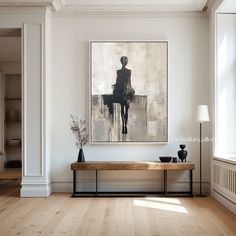 a painting hangs on the wall above a wooden bench in an empty room with white walls