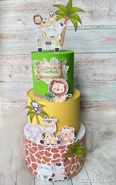 a three tiered cake with animals and palm trees on the top is made out of paper