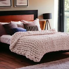 a bedroom with a large bed covered in blankets and pillows, along with pictures on the wall