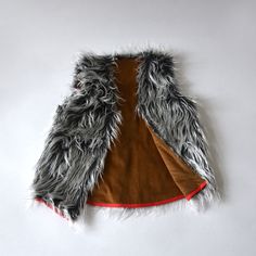 a jacket with fur on it sitting on top of a white floor next to a wall