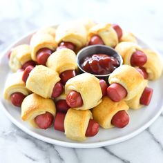 a white plate topped with pigs in a blanket covered in ketchup and mustard