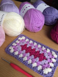 several balls of yarn sitting next to each other on a wooden table with crochet hooks