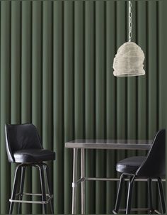 two chairs and a table in front of a green wall with vertical blinds on it