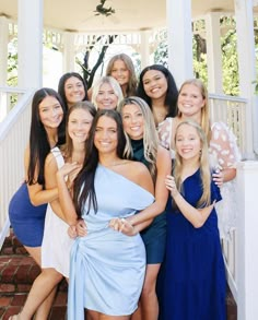 a group of women standing next to each other in front of a gazebo on a sunny day