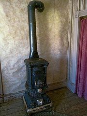 an old fashioned stove is in the corner of a room with pink drapes on the walls