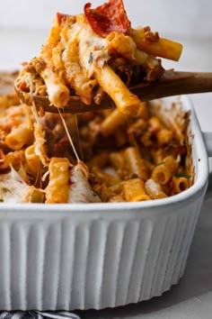 a casserole dish with pasta and meat being lifted from the casserole