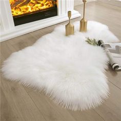 a white sheepskin rug on the floor in front of an open fire place with candles