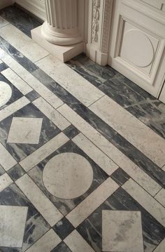 a marble floor with white and black designs on the tile, next to a door