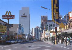 an old photo of people walking down the street in front of mcdonald's and other buildings