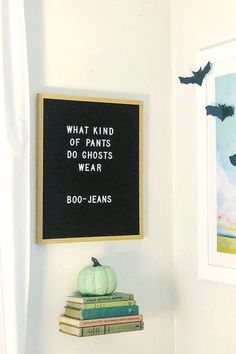 a blackboard hanging on the wall next to some books and a pumpkin with bats